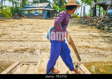 THAZIN, MYANMAR - FEBRUARY 28, 2018: The raftman uses the plank to push off the river's bank with a view on village houses on background, on February  Stock Photo