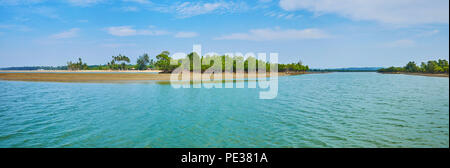 Panorama of the estuary of Pathein river tributary with land spit, covered by lush mangroves at the low tide, Chaung Tha, Myanmar. Stock Photo