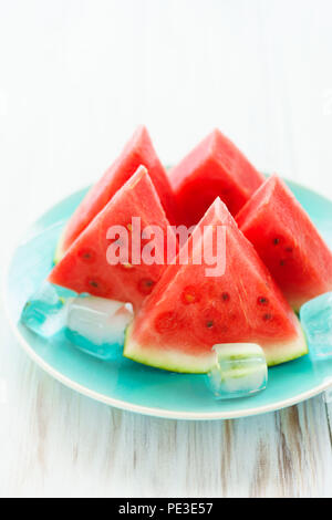Watermelon slices on a blue plate with ice cubes. White wooden background, high resolution Stock Photo