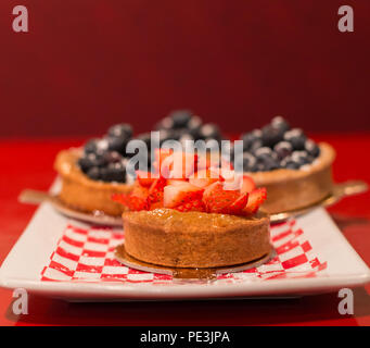 Strawberry tart with blueberry tarts in the background. Stock Photo