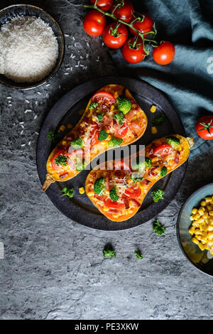 Roasted Butternut Squash stuffed with rice, bacon, broccoli, tomato, corn and cheese Stock Photo