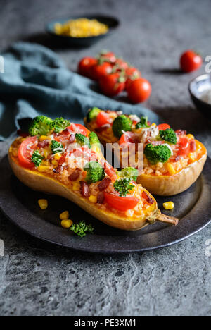 Roasted Butternut Squash stuffed with rice, bacon, broccoli, tomato, corn and cheese Stock Photo