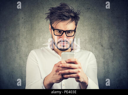 stunned man, surprised offended, shocked by what he sees on his smartphone Stock Photo