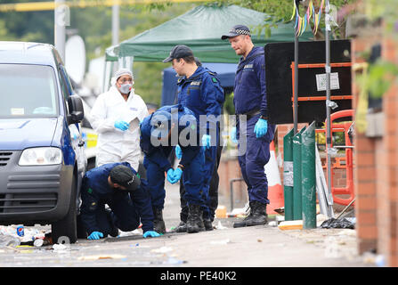 Police from the Tactical Aid Unit carry out a fingertip search in Claremont Road, Moss Side, Manchester, where ten people, including two children were taken to hospital after reports of gunshots at a street party. Stock Photo