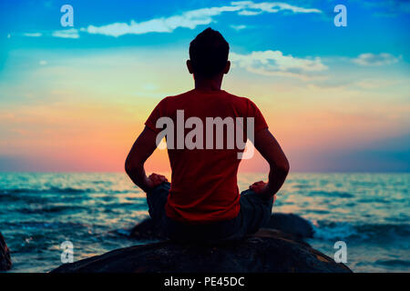 People practicing yoga pose and meditation on tropical beach at sunset Stock Photo