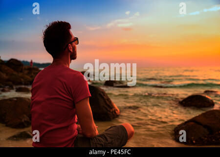 People practicing yoga pose and meditation on tropical beach at sunset Stock Photo