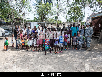 U.S. Marines, Soldiers and members of the U.S. Embassy, pose for a group photo with children and staff from an orphanage in Leogane, Haiti during Operation Continuing Promise, Sept. 9, 2015. Operation Continuing Promise is a mission to countries in Central and South America and the Caribbean, where the U.S. Military and its partnering nations work with host nations and a variety of governmental and non-governmental agencies in civil-military operations. (U.S. Marine Corps photo by Sgt. James R. Skelton/Released) Stock Photo