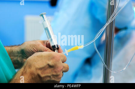 Doctor's hand and infusion drip in hospital on blurred backgroun Stock Photo