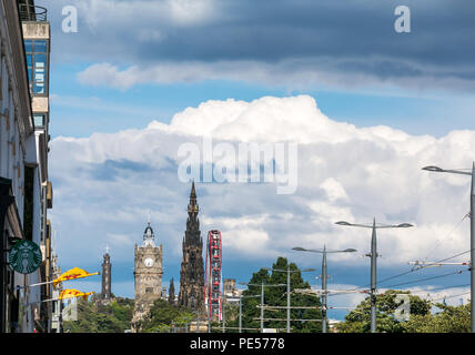 View along Princes Street with overhead tram wires, Scott monument, Balmoral Hotel clock tower and M&Ds Big Ferris Wheel during Summer festival season Stock Photo