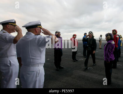 151001-N-EM227-014 TOKYO BAY, Japan (Oct. 1, 2015) Capt. Christopher Bolt, (far left) commanding officer USS Ronald Reagan (CVN 76), and Rear Adm. John Alexander, (left), commander, Battle Force 7th Fleet, salute Secretary of the Navy (SECNAV) Ray Mabus during a visit aboard the U.S. Navy’s only forward-deployed aircraft carrier USS Ronald Reagan (CVN 76). Ronald Reagan and its embarked air wing, Carrier Air Wing (CVW) 5, provide a combat-ready force that protects the collective maritime interests of its allies and partners in the Indo-Asia-Pacific Region. (U.S. Navy photo by Mass Communicatio Stock Photo