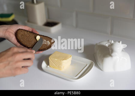 Woman smears butter with a knife on bread. A Healthy Eating Concept Stock Photo