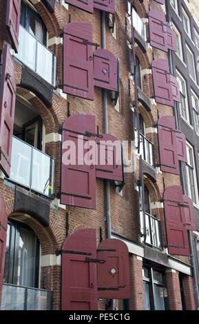 Amsterdam apartment building with red open wooden window shutters Stock Photo