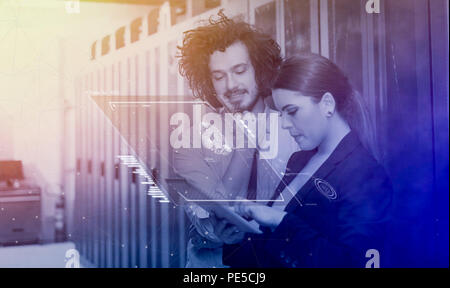 Young IT engineer showing working data center server room to female chief engineer who holding tablet computer Stock Photo
