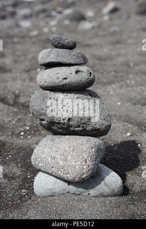 Balanced stacked stones or pebbles on a black sand beach. Stock Photo