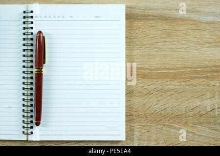 Fountain pen or ink pen with notebook paper on wooden working table with copy space, office desk concept idea. top view. Stock Photo