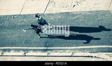 Silhouette of a two womans casting a long shadow on a asphalt road Stock Photo