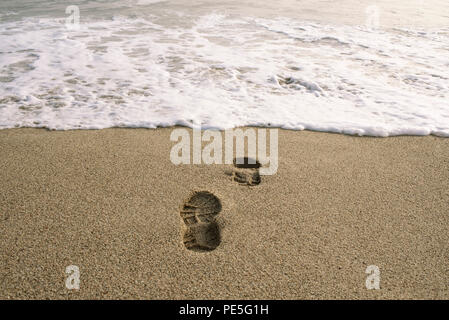 Swallowed by the sea. Conceptual image of shoe footprints in sand. Punta Hermosa, Peru. Jul 2018 Stock Photo