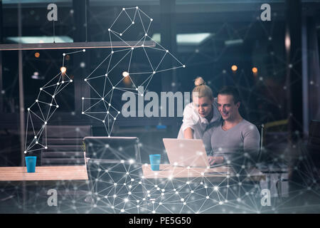 Two young designers are working on a new project in the night office using modern technology Stock Photo