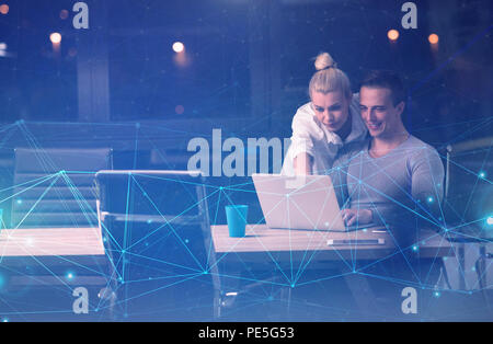 Two young designers are working on a new project in the night office using modern technology Stock Photo