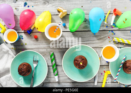 Flat lay children birthday table. Chocolate muffins and decoration party on wooden background top view Stock Photo