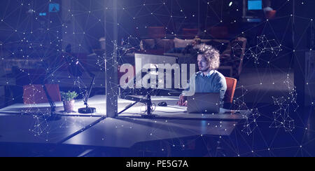 Young man working on computer at night in dark office. The designer works in the later time. Stock Photo