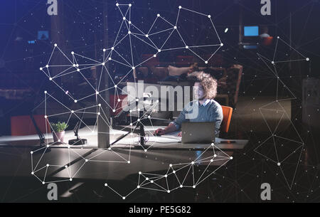 Young man working on computer at night in dark office. The designer works in the later time. Stock Photo