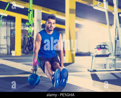 Young strong man doing pushups on kettlebells at cross fitness gym Stock Photo