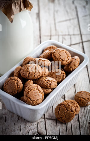 meringue almond cookies in a bowl and bottle of milk on wooden background Stock Photo