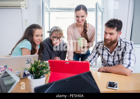 Four co-workers watching a business presentation in a modern shared office space Stock Photo
