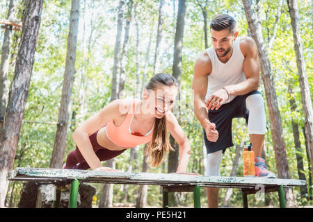 Sporty woman doing push-up in an outdoor gym Stock Photo