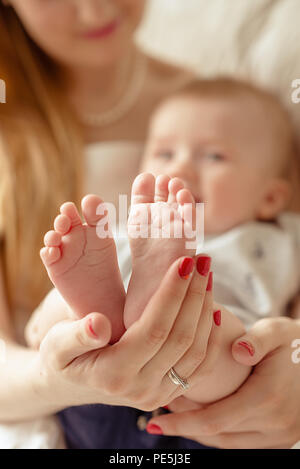 Baby feet in mother hands. Mom and her Child. Happy Family concept. Beautiful conceptual image of Maternity Stock Photo