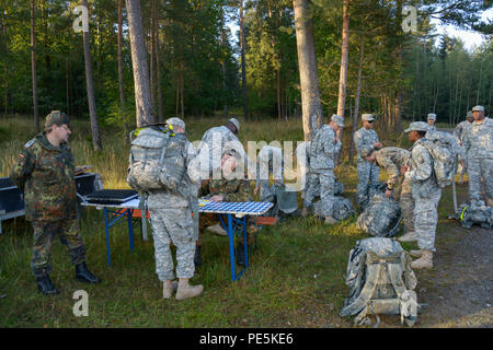 German army, Command Sgt. Major Gerhard Lindthaler, from Freihung Reserve Association, conduct an equipment inspection prior to a 12K ruck march for the U.S. Soldiers, assigned to 18th Combat Sustainment Support Battalion and 2nd Cavalry Regiment, during qualification for the German Foreign Award or Leistungsübersicht at the Grafenwoehr Training Area, Germany, Sept. 22, 2015. The soldiers must complete a series of events to earn the German Foreign Award or Leistungsübersicht. (U.S. Army photo by Spc. Nathanael Mercado/Released) Stock Photo