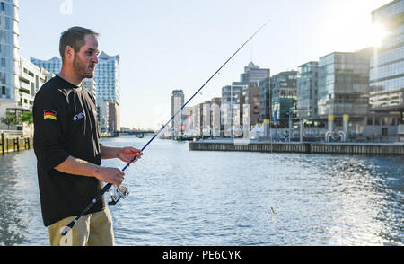 Hamburg, Germany. 02nd July, 2018. Gordon Naumann, street fisherman, is fishing at the Magellan Terraces in the Hafencity. Street fishermen conquer Hamburg's rivers and canalss. Young street fishermen hunt for fresh fish in the middle of Hamburg and give the traditional hobby a new image. Credit: Axel Heimken/dpa/Alamy Live News Stock Photo