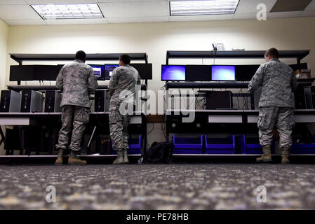 Airmen from the 92nd Communications Squadron at Fairchild Air Force Base, Washington, apply security patches to computer systems on October 29, 2015. The work ensures mission readiness and cyber safety for the 36th Rescue Flight and 92nd Air Refueling Wing. Client systems technicians manage software updates, system integrity, and network functionality to maintain operational capability. Security patching protects computing infrastructure, safeguards sensitive data, and supports mission-critical communications. Stock Photo