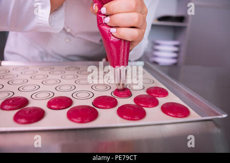 Female baker using pastry bag while cooking pink marshmallows Stock Photo