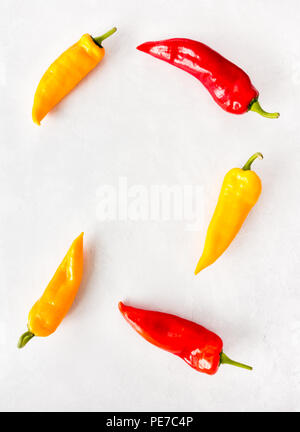 Red, Yellow and Orange Romano Peppers on Light Gray Textured and Patterned background with copy space. Stock Photo