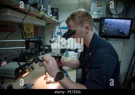Electronics Technician 2nd Class conducts motherboard repairs aboard the Wasp-class amphibious assault ship USS Essex (LHD 2) in the Indian Ocean on November 5, 2015. Essex is flagship of the Essex Amphibious Ready Group and operates with the embarked 15th Marine Expeditionary Unit in the U.S. 7th Fleet area of responsibility. Operations emphasize technical proficiency, maintenance, communications support, and integration of shipboard electronic systems during deployment. Stock Photo