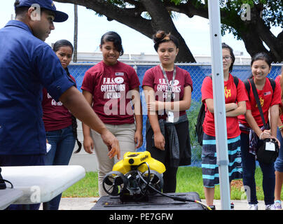 A Coast Guard electrician demonstrates a remotely operated vehicle to students during a STEM exposition at Coast Guard Base Honolulu on October 15, 2015. Over 100 teens from Oahu schools learn about Coast Guard missions, robotics, technology, and engineering career opportunities. The demonstration provides hands-on experience in equipment operation, safety protocols, and maritime security procedures. Stock Photo