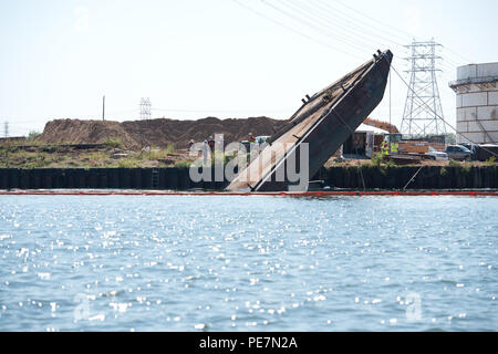 A barge sits almost vertical in the upper Houston Ship Channel with a boom surrounding it after it became submerged around 5 a.m. Monday, Oct. 19, 2015. Coast Guard Vessel Traffic Service Houston received a radio call from a good Samaritan who saw the vessel sinking. Stock Photo