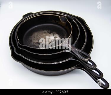 used stacked cast iron skillets on white background Stock Photo
