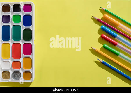 Top view of Work Process Blank Watercolor Paper pad, Watercolor Painting Supplies, Brushes and Colorful Pencil on yellow. Creation process of watercolor painting. Copy space. Stock Photo