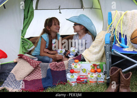 Two girls having fun camping with their Buddy Fruits Stock Photo