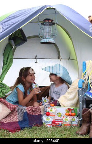 Two girls having fun camping with their Buddy Fruits Stock Photo
