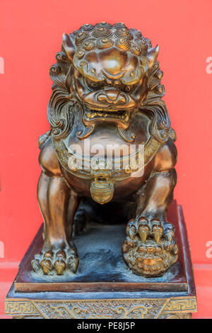 Bronze Chinese lion sculpture, male of the pair, holding a baby in her front paw, symbol of protection and power in Asia