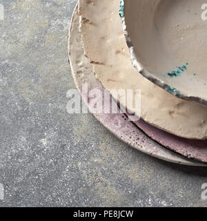 Handcrafted clay empty bowls and plates covered with glazed on a gray concrete background. Stock Photo