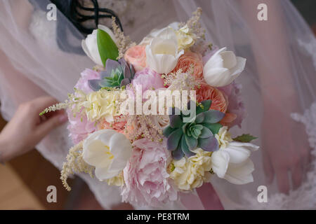 Close-up on Caucasian woman's hands holding an elegant bridal bouquet, with soft, pink hues Stock Photo