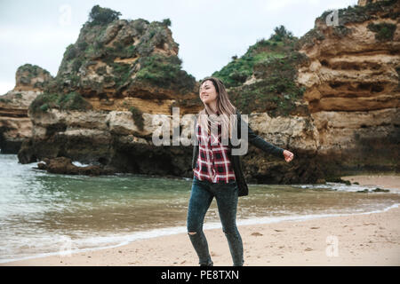 A young beautiful girl runs around the Atlantic coast in Portugal and enjoys life and rejoices. Stock Photo