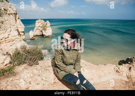 A young woman tourist enjoys the beautiful views of the Atlantic Ocean and the landscape off the coast in Portugal. Stock Photo