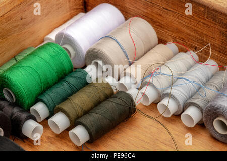 A closeup photo of sewing thread spools, beige and brown, in a wooden box Stock Photo