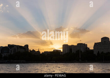 Crepuscular rays seen from the South Bank of the River Thames as the sun sets in London, UK in August 2018 Stock Photo